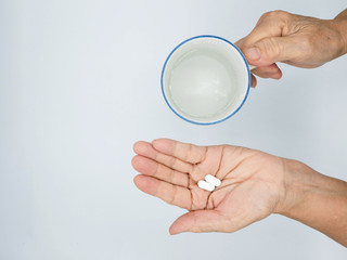 top view of woman holding pill in one hand and glass of water ,Taking Your Medication.