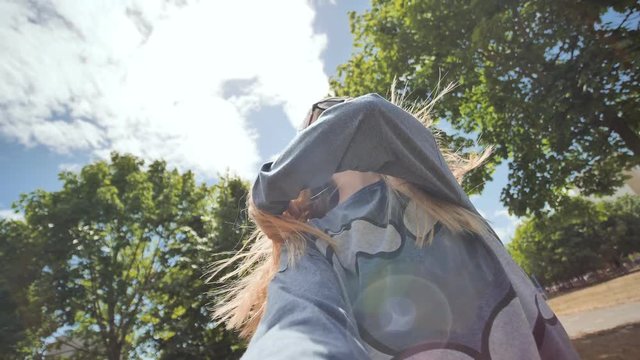Beautiful twelve-year-old teenager girl takes a selfie with a video camera on the background of sun rays and trees