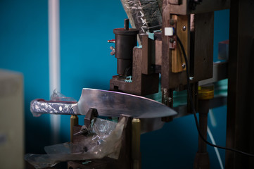 Knife blade making test cut with paper on machinery, manufacturing closeup