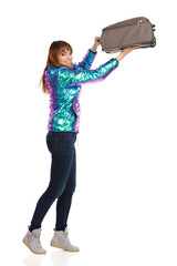 Young Woman In Vibrant Down Jacket Puts The Luggage Up Looks At Camera And Smiles