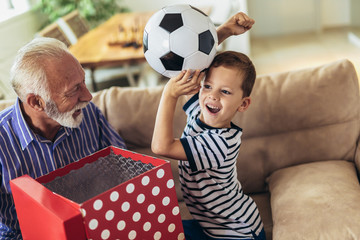 Handsome senior grandfather presenting gift to happy grandson