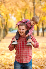 Father and son are playing and having fun in autumn city park. They posing, smiling, playing....