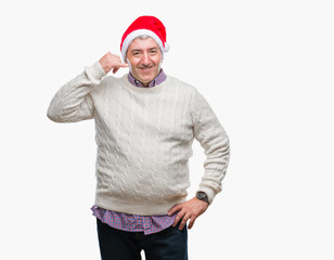 Handsome senior man wearing christmas hat over isolated background smiling doing phone gesture with hand and fingers like talking on the telephone. Communicating concepts.