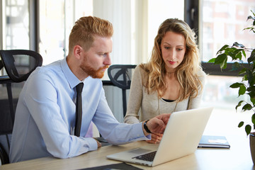 Two colleagues looking into laptops screen