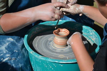 hands of potter creating a jar on circle