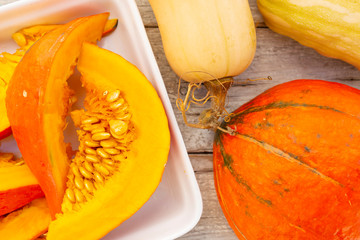 Sliced ripe pumpkin on a wooden kitchen table.
