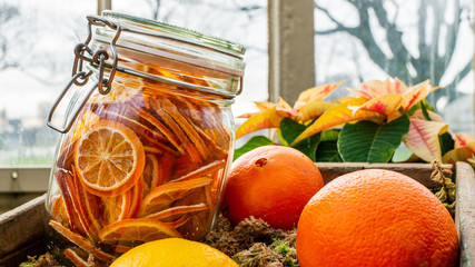 Jar of dried orange slices in a wooden fruit crate. Winter holidays decor.
