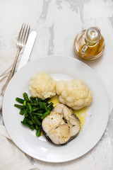 boiled fish with boiled vegetables on white plate