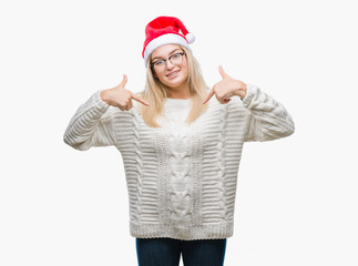 Young caucasian woman wearing christmas hat over isolated background looking confident with smile on face, pointing oneself with fingers proud and happy.