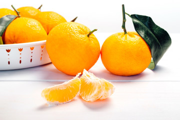 Pile of mandarins in white bowl on white wooden background