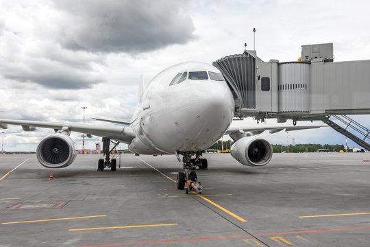 Passenger airplane in the parking at the airport with a nose forward and a gangway