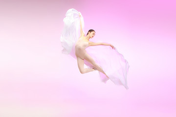Young graceful female ballet dancer or classic ballerina dancing at pink studio. Caucasian model on...