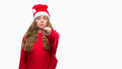 Young blonde woman wearing santa claus hat pointing with finger to the camera and to you, hand sign, positive and confident gesture from the front
