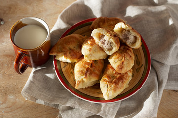 Russian meat piroshki. Traditional hand mini pies on wooden background