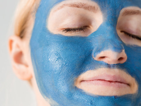 Skin care. Woman face with blue clay mud mask close up. Girl taking care of oily complexion. Beauty treatment.