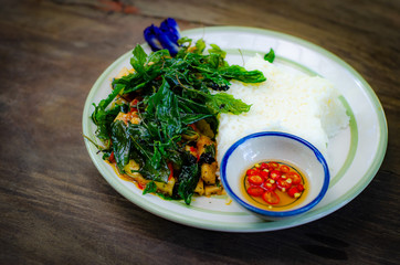 fried rice with basil on old wood background.