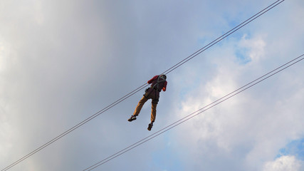 A man playing zip line with sky background.