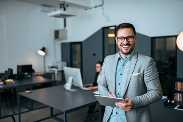 Portrait of a smiling handsome business man in coworking office. Looking at camera.