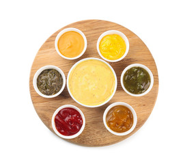 Wooden board with tasty sauces in bowls on white background