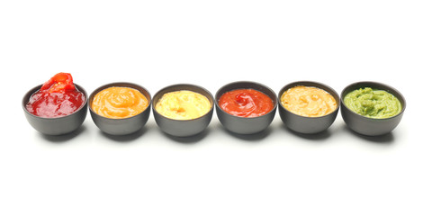 Different tasty sauces in bowls on white background