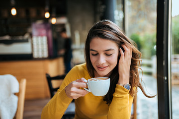 Gorgeous girl drinking coffee in the cafe. Front view. - obrazy, fototapety, plakaty