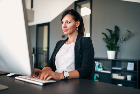 Portrait of beautiful businesswoman working on computer in modern office.