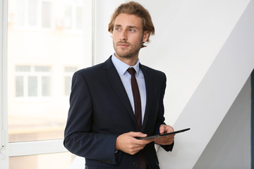 Successful businessman with tablet computer near window