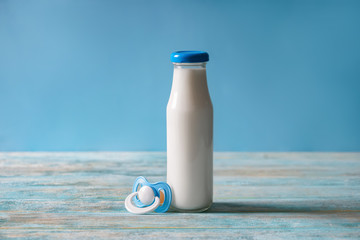 Bottle of milk and pacifier on wooden table