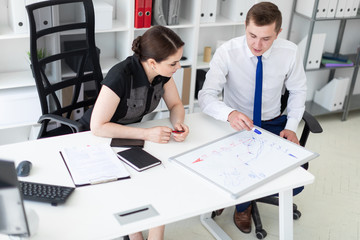 Obraz premium Young people in the office discussing the schedule on a magnetic Board.