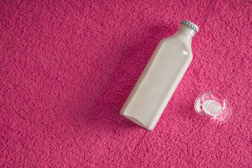 Bottle of milk and pacifier on soft towel, top view