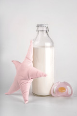 Obraz na płótnie Canvas Bottle of milk with baby toy and pacifier white background