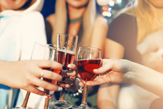 Cheers! Girls friends having xmas party and drinking red shampagne. Toasting with glasses of wine on the smiling womans backgroung. New year party