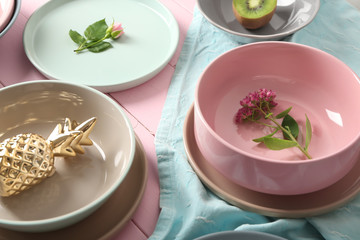 Tableware, flowers and decorations on pink wooden background