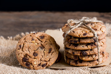 Chocolate chip cookies freshly baked on sackcloth on wooden table background. Homemade pastry. With copy space for text and logo.