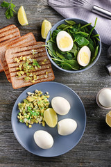 Boiled eggs with toasted bread and spinach on wooden table