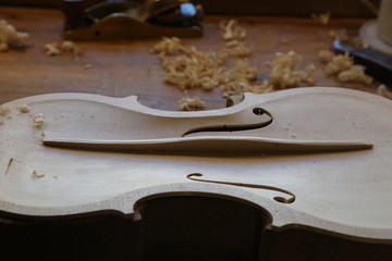  Unfinished violin in luthier, violin maker workshop. Upper face of a violin with the f visible, not lacquered yet, without strings, 