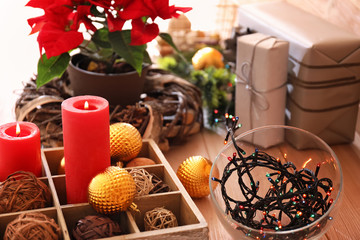 Burning candles with decorations and Christmas flower poinsettia on table