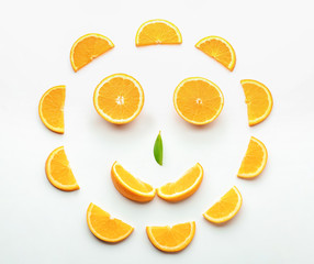Funny face made of tasty cut orange on white background