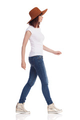 Young Woman In White T-Shirt, Hat And Gold Sneakers Is Walking And Looking Away