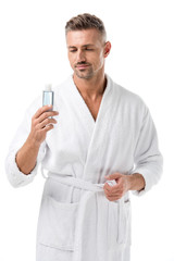 man in bathrobe holding shaving lotion isolated on white