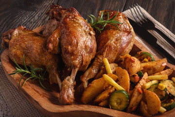 Roasted duck legs with apples and cranberries, served with vegetables.