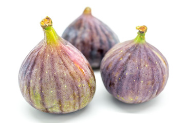 Three figs against a white background, with a shallow depth of field
