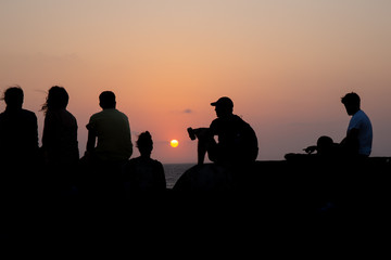 Fototapeta na wymiar Grupo de gente y puesta de sol frente al mar