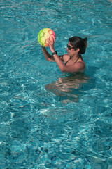 Woman playing with a ball in the swimming pool - copy space. 