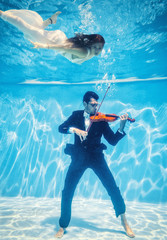 Violinist underwater with muse swimming around