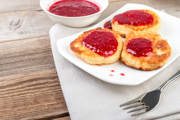 Cottage cheese pancakes, cheesecakes  with raspeberry  jam on wooden background, healthy traditional  breakfast
