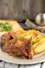 Roast pork with herbs and vegetables on rustic wooden table.