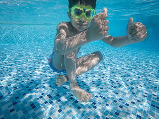 A boy poses for the camera under water in a swimming pool on holiday. 