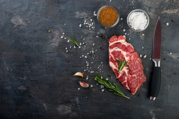 Raw beef steak with spices on black background. Flat lay.Top view