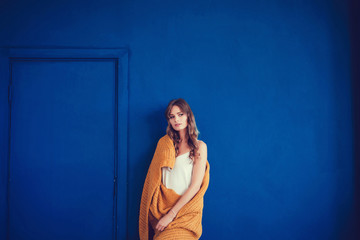 Cozy woman covered with warm wool blanket on blue background. Relax, comfort lifestyle.
